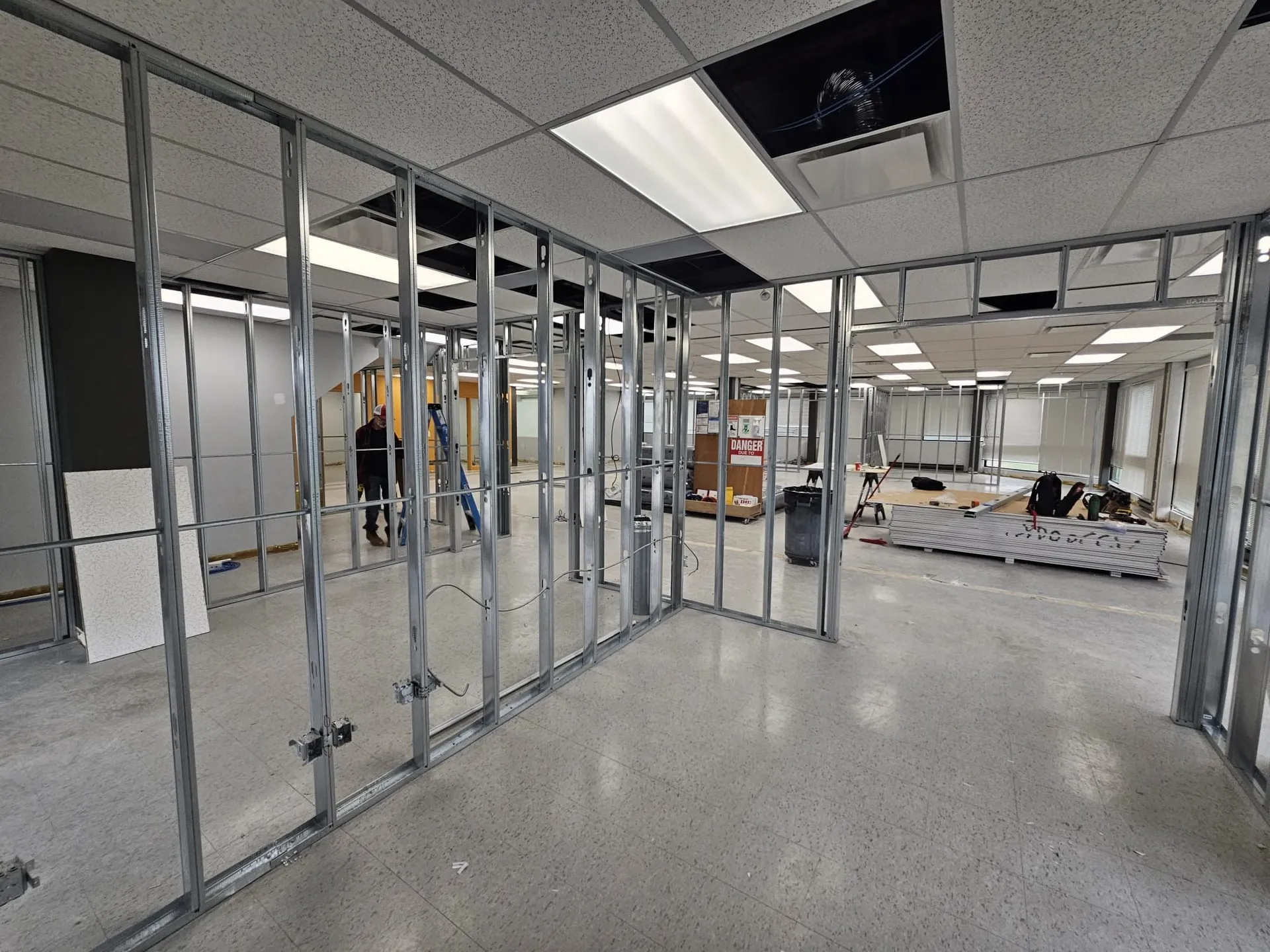 Steel-stud framing with a crew member working in the background and materials staged