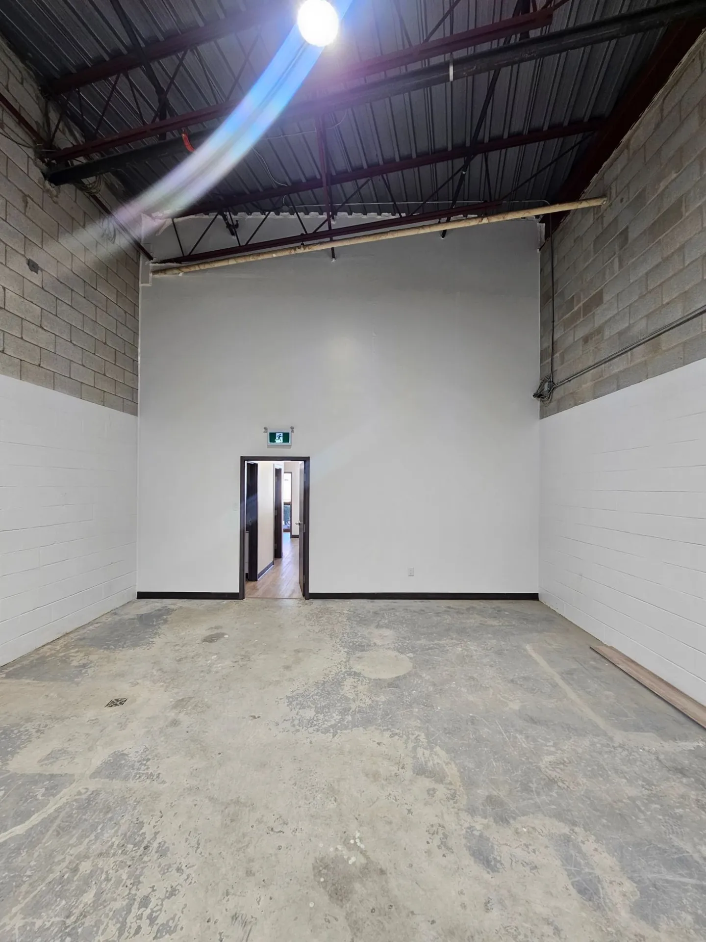 New white demising wall between block walls in a high-ceiling warehouse